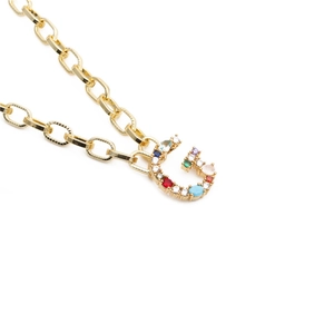 Detailed view of golden chain necklace with letter C pendant and colorful zircons