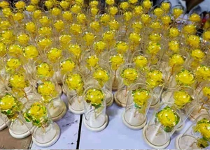 Batch of yellow gold foil roses in glass domes with light wood bases on a factory table