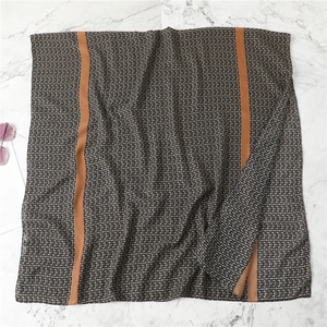 Flat lay of a grey scarf with orange stripes and G pattern on marble surface