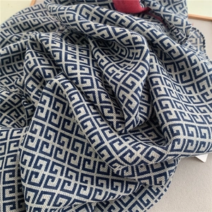 Close-up of soft linen-touch scarf with dark blue and beige geometric fretwork pattern