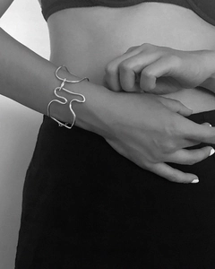 Macro shot of minimalist silver cuff bracelet with abstract irregular wave pattern