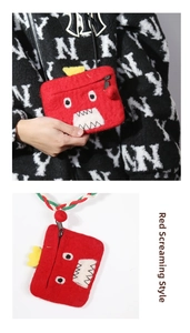 Detail view of red monster felt coin purse with white jagged mouth and woven strap