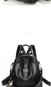 Detail of black soft PU leather backpack with heart metal logo and cow plush pendant
