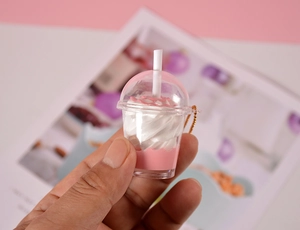 Gros plan détaillé d'un porte-clés miniature thé au lait rose tenu à la main pour la taille