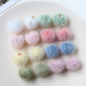 Close-up of colorful plush ball pendants with gold rings for DIY jewelry making