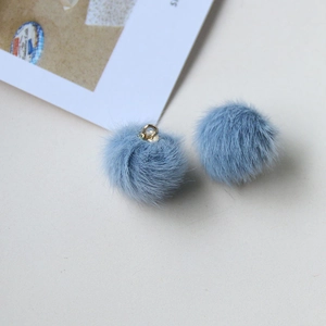 Close-up of soft light blue plush ball pendants with golden metal rings for DIY jewelry