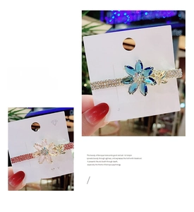 Detailed view of crystal flower hair clips in pink and blue with gold butterfly accents