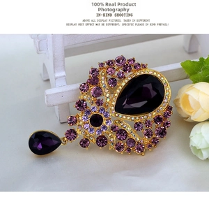 Macro detail of a vintage purple rhinestone brooch with a gold setting and teardrop pendant