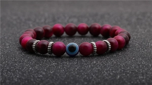 Detail shot of 8mm rose red tiger eye stone beads with a blue evil eye bead on a bracelet