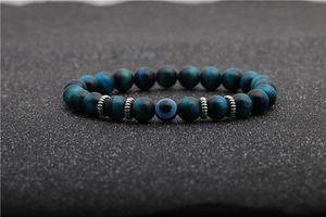 Macro shot of 8mm tiger eye beads with a centered evil eye and silver spacers