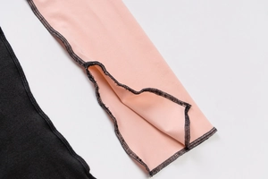 Close-up of pink and black fabric with detailed black contrast stitching and overlock seams