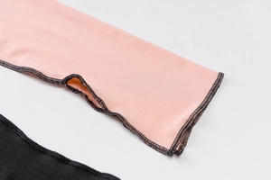 Detail of pink and black knit fabric featuring professional contrast overlock stitching