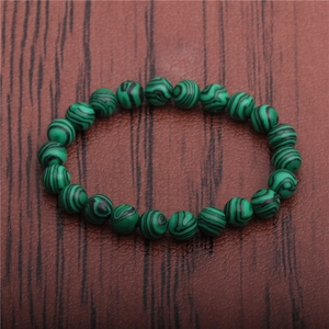 Detail of 8mm green malachite texture beads on wooden surface for stretch bracelet