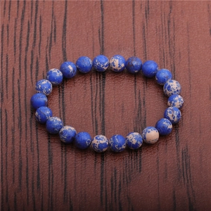 Detail of 8mm blue emperor stone beads with marble texture on brown leather surface