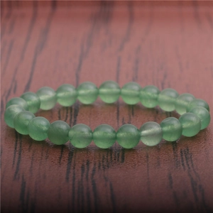 Macro shot of 8mm green tiger eye stone beads bracelet on a rustic wood background
