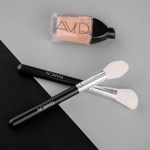 Close-up of dual makeup brushes with white bristles, black handles, and silver metal ferrule