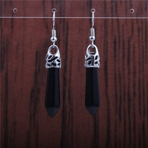 Detail of silver drop earrings with hollow metal charms and black hexagonal stone prisms