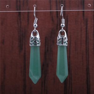Close-up of green crystal cylinder earrings with ornate silver caps and ear hooks