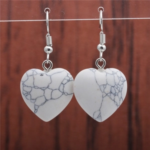 Macro shot of white turquoise heart drop earrings with silver fishhook ear wires