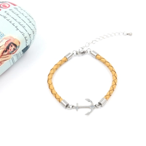 Detail of yellow braided leather bracelet with silver anchor charm and adjustable chain