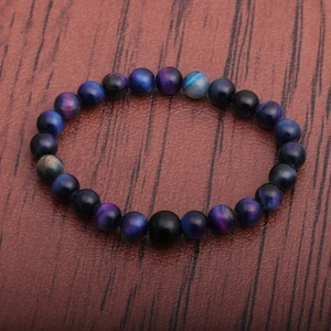 Macro shot of blue and purple tiger eye beads bracelet on dark wood surface