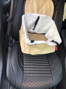 Detail of beige fabric car booster seat for pets featuring secure nylon straps and hooks