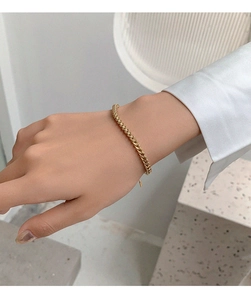 Close-up of a gold-plated woven titanium steel chain bracelet worn on a woman's wrist