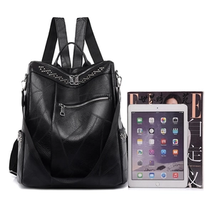 Zaino in ecopelle nera con borchie argento e motivi geometrici accanto a un iPad