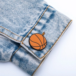 Gros plan d'un pin's de basketball en émail sur la manche d'une veste en jean