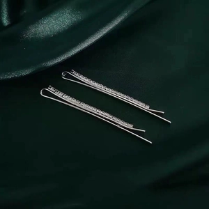 Sparkling silver rhinestone hair clip set on elegant dark green silk fabric background