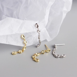 Macro shot of liquid metal drop earrings in gold and silver finish with tassel design