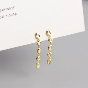 Detail of gold-tone earrings with five cascading irregular hammered metal pebbles
