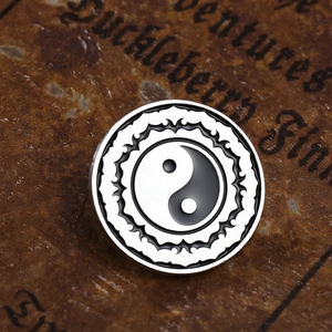 Makroaufnahme der Yin-Yang-Tai-Chi-Emaille-Nadel mit Lotusmustern auf Vintage-Buch