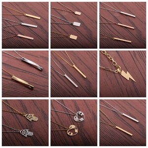 Assorted stainless steel pendant necklaces in gold and silver on a dark wood background