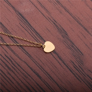 Collier avec pendentif cœur doré en acier inoxydable sur fond en bois rustique