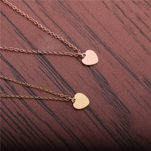 Collier avec pendentif cœur en acier titane doré et or rose sur fond de bois sombre