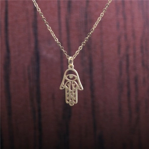 Golden titanium steel Hamsa Hand pendant necklace with evil eye on a wood surface