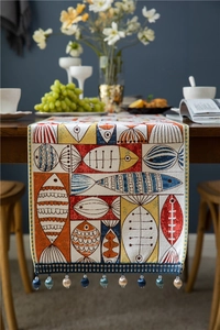 Detail of chenille table runner featuring colorful fish patterns and blue beaded tassels