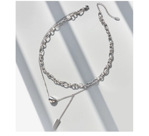 Detail of silver double-layered necklace with square tag and semi-circle pendant