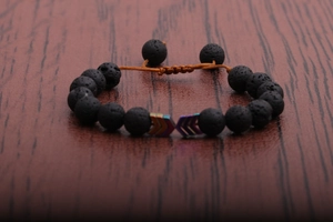 Close-up of adjustable volcanic stone bead bracelet with colorful metal arrow charms