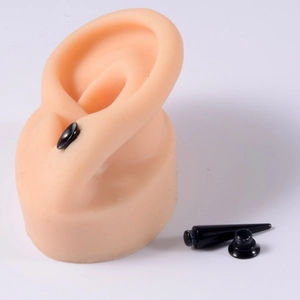 Detail view of black acrylic ear taper and double flared tunnel on skin silicone ear model