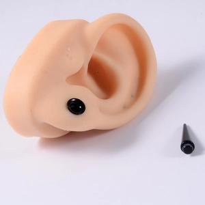 Detailed view of black acrylic ear gauge and taper on a silicone ear display model