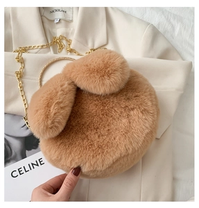 Detail of plush rabbit ear bag featuring a golden ring handle and elegant chain strap