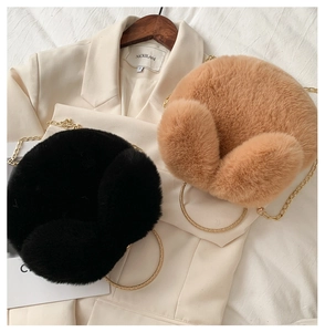 Detail of round plush bags in black and camel featuring gold chain and circular metal handles