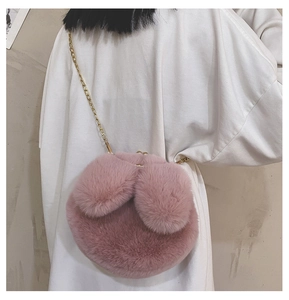 Pink plush rabbit ear crossbody bag with gold chain strap worn by a model