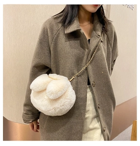 Detail of plush bunny ear crossbody bag in cream white with a golden chain strap