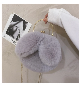 Detail of purple faux fur bag with rabbit ears and gold circular handle held by a model