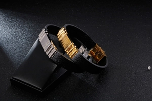 Dettaglio di bracciali in pelle con inserti in acciaio inox oro e argento su base nera