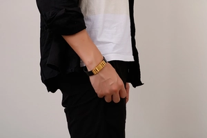 Dettaglio del bracciale da uomo intrecciato in pelle nera e acciaio inossidabile dorato