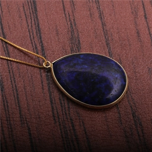 Macro shot of dark blue teardrop gemstone pendant on a fine golden necklace chain